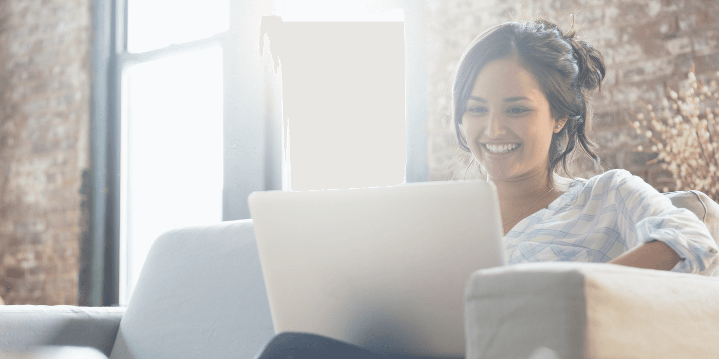 person sitting on couch, looking at laptop and smiling