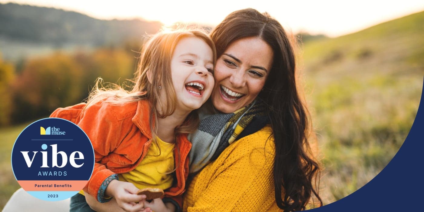 A mother and daughter embracing and laughing outdoors.